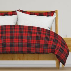 a red and black plaid comforter on a bed with two pillows in front of it