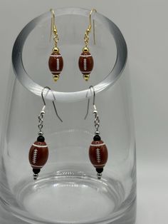 Show some team spirit with these football earrings! An acrylic football paired with metal and gemstone beads in various color combinations. Don't see one in your team colors? Message us and we'll be happy to make one.  As each piece is handmade, there may be slight variations in each.  Listing includes hypoallergenic ear wires; however, if you prefer .925 Sterling Silver or Gold Filled ear wires, please message us for a custom order.  Caring for your jewelry means you will enjoy its beauty for a Team Spirit Round Beads Jewelry For Game Day, Black Team Spirit Jewelry For Game Day, Football Earrings, Vendor Events, Beads Charms, Sports Teams, Etsy Earrings Dangle, Color Calibration, How To Apply Makeup