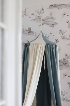 a canopy bed hanging from the ceiling in front of a wallpapered room with birds on it