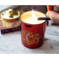 a person lighting a candle in a red cup