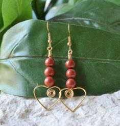 These earrings feature 3 6mm round red jasper beads strung on gold-plated wire shaped into a scroll heart at the bottom.       Earrings are approximately 2.5" long, including gold-plated ear wires.   Wire hearts are .75 inches wide.   Rubber ear nuts are included. Nickel-free Jasper Earrings As Gift, Nickel-free Jasper Earrings For Gifts, Handmade Jasper Earrings As Gift, Elegant Adjustable Heart Beads Earrings, Elegant Heart Beads Earrings, Red Jasper Jewelry, Wire Hearts, Jasper Jewelry, Jasper Earrings