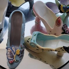 several pairs of shoes sitting on top of a glass table with flowers and butterflies painted on them