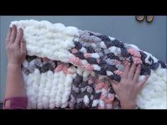 a woman is holding up a blanket made out of knitted wool and yarn balls