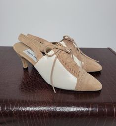 These vintage Newport News point toe heels are DIVINE! I'm placing them from the late 80s  to early 90s era. The material is a fine ivory leather upper with contrasting tan suede. They feature a stiletto heel, a faux lace up front, and have a sling back strap. Condition: Great vintage condition with original box. These shoes appear to have never been worn and are sold with the original box. The tap piece on the heel is brand new. The only flaw is that the vinyl interior lining is beginning to dry rot and flake off. Please view all pictures carefully as all vintage items are sold as is. Label: Newport News Label Size: 7 B For more vintage and handmade women's and children's clothing please visit my shop: www.etsy.com/shop/WhimsyFair Thanks for visiting Whimsy Fair! Retro Beige Leather Heels, Cream Kitten Heels With Sculpted Heel And Pointed Toe, Retro Beige High Heels, Beige Kitten Heels With Almond Toe, Vintage Open Toe Suede Heels, Cream Kitten Heels With Padded Heel And Almond Toe, Beige Retro Open Toe Heels, Vintage Beige Pointed Toe Heels, Vintage Kitten Heels With Pointed Toe For Spring