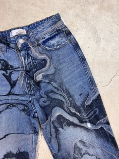 an old pair of blue jeans with black and white designs on them sitting on the ground