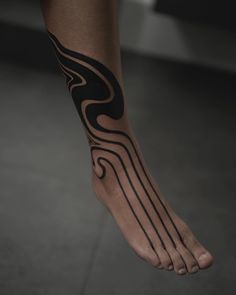 a person with a black and white tattoo on their foot is standing in the floor