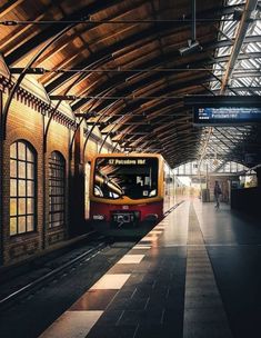 a red and yellow train pulling into a train station