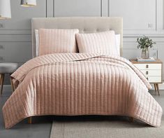 a bed with pink comforter and pillows