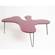 a pink coffee table with black hairpinks on the legs and an upside down design