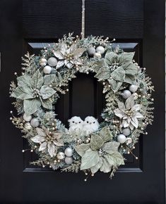 a wreath with an owl on it is hanging from the front door, decorated with silver and white ornaments