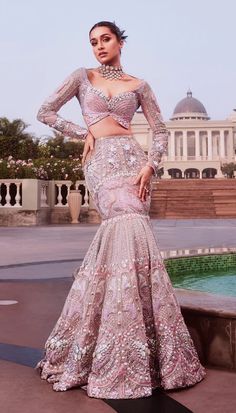 A 3-piece mermaid cut lehenga in lilac embroidered with silver metal embellishments, precious crystals, 3D flower and glass cut beads. This lehenga is completed with a waist side-cut covered with tulle and silver embroidered tassles Paired with a singature Papa Don't Preach butterfly full sleeved blouse qppliqued in lilac silks. This look is completed with a tissue organza embroidered dupatta in lilac. DELIVERY TIMEPlease wait 8-12 weeks for your outfit to arrive. FABRIC DETAILSTulle Professiona Glamorous Floor-length Sharara With Pearl Embroidery, Glamorous Pink Lehenga With Intricate Embroidery, Glamorous Fitted Hand Embellished Lehenga, Glamorous Fitted Gown For Designer Wear, Glamorous Pink Sharara, Elegant Purple Sequined Sharara, Elegant Embellished Purple Choli, Hand Embellished Purple Lehenga For Wedding, Expression Queen