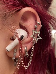 a woman with red hair has ear piercings on her ears and is holding a pen