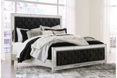 a white bed with black and silver pillows