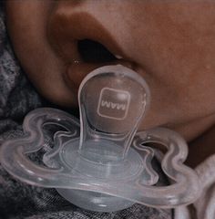 a close up of a person holding a pacifier in their mouth with the word num written on it