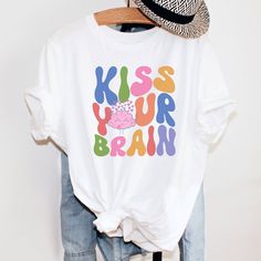 "Perfect gift for a Teacher or Special Education Teacher. I have said, \"Kiss your Brain,\" so many times in my classroom. This super cute retro teacher shirt makes a great teacher appreciation gift or a gift for a new graduating teacher. This is such a comfy, soft Tee with a loose fit, perfect to go with your favorite leggings. I use Bella+ Canvas t-shirts. UNISEX sizing they are meant to have a loose fit. Please refer to our sizing chart in the photos for measurements. *If you are looking for Fun T-shirt With Funny Print For Teacher Appreciation, Retro Crew Neck T-shirt For Teacher Appreciation, Cute Multicolor Slogan T-shirt, Cute Multicolor T-shirt With Slogan, Fun Graphic Print T-shirt For Teacher Appreciation, Fun Slogan Tops For School, White Funny Print T-shirt For School, Fun Letter Print Shirt For Teacher Appreciation, Fun Teacher Appreciation T-shirt With Graphic Print