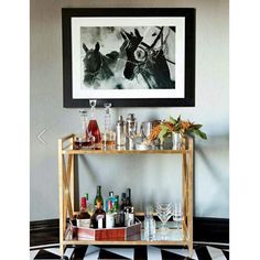 a bar cart filled with bottles and glasses on top of a black and white checkered floor