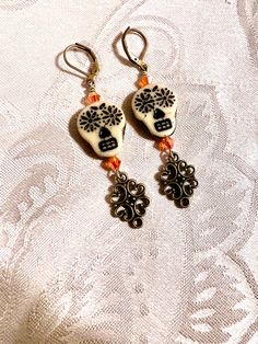 the earrings are decorated with black and white flowers on orange beaded corded earwires