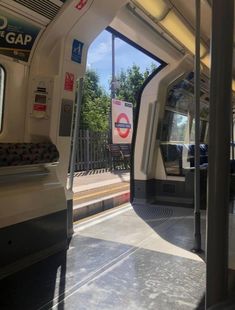 the inside of a subway car with its doors open and trees in the background,