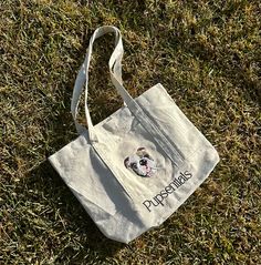 Carry your love for your pet everywhere with our Pupsentials Custom Pet Canvas Tote Bag! This bag is perfect for your trips to the farmers market, school, work, or just about anywhere.** Please note the pocket on the front of the tote is non functioning due to the embroidery being stitched into the bag**** Bags come WITHOUT "Pupsentials" Name under. If you like to add your pet's name it is $10 & please request on your order notes. If you want to do a different pet for the free tote - reach out a Rectangular Shoulder Bag With Embroidered Logo, Rectangular Shoulder Bag With Embroidered Logo For Everyday, Rectangular Everyday Shoulder Bag With Embroidered Logo, Everyday Shoulder Bag With Embroidered Logo, Everyday Rectangular Bags With Embroidered Logo, Everyday Tote Shoulder Bag With Embroidered Logo, Casual Tote Bag With Embroidered Logo, Rectangular Canvas Bag With Embroidered Logo For Everyday Use, Casual School Bag With Embroidered Logo