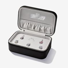 an open jewelry box with four pairs of earrings in it on a white table top