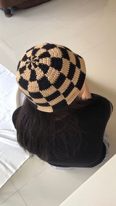 a woman sitting on the floor wearing a black and white knitted hat with spiral design