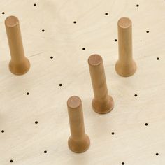 four wooden pegs on top of a table with holes in the wood and dots around them