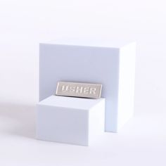 a white object with a silver name plate on it's side and another item in the background