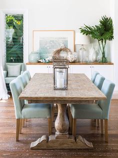 a dining room table with blue chairs and a lantern on the centerpiece in front of it