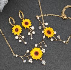 three sunflowers and pearls are attached to gold chains on a black surface,