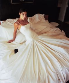 a woman laying on top of a bed covered in white sheets