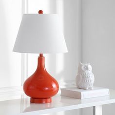 an orange lamp sitting on top of a white table next to a small owl figurine