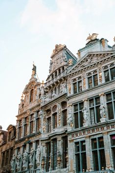 an old building with statues on the front and side of it's windows, against a blue sky