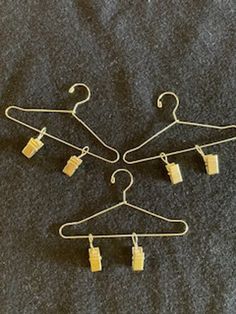 three pairs of clothes hangers with clips attached to them on a gray cloth background