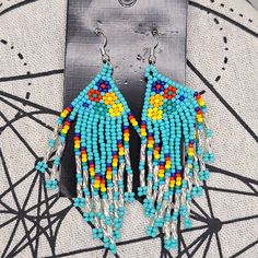 a pair of colorful beaded earrings sitting on top of a piece of paper next to a