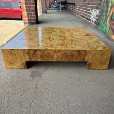 a wooden table sitting on the side of a road next to a brick wall with graffiti