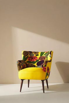 a yellow chair sitting in the middle of a room with a white wall behind it