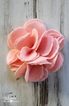 a pink flower sitting on top of a white wooden table next to a piece of wood