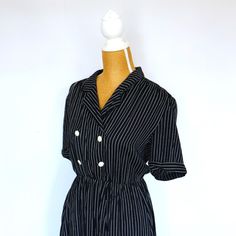 1990s vintage black and white pinstripe tea dress. A classic dress featuring midi-length hem, short sleeves, and a collared neckline with double-button detailing to the bodice, sailorcore style. There is an elasticated waist with belt loops to accessorise with a belt should you wish. There are 2 side pockets. This dress is made from viscose and is both stylish and easy to wear.  Size - small to medium Chest - 32" / 81cm Waist - 24" to 30" / 61cm to 76cm Hips - 34" / 86cm Length - 44" / 112cm Con Fitted Short Sleeve Dress With Vertical Stripes, Fitted Dress With Vertical Stripes And Short Sleeves, Classic Black Short Sleeve Vintage Dress, Short Sleeve Dresses With Vertical Stripes For Work, Vintage Striped Workwear Dresses, Retro Striped Dresses With Buttons, Vintage Striped Dress For Work, Vintage Striped Dresses For Work, Striped Retro Dresses With Buttons