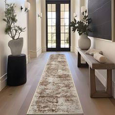 a long hallway with a rug on the floor and two vases in front of it