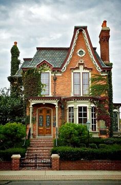 an old brick house with ivy growing on it's roof and stairs leading up to the front door