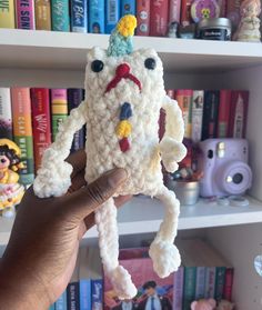 someone is holding up a crocheted toy that looks like a unicorn's head