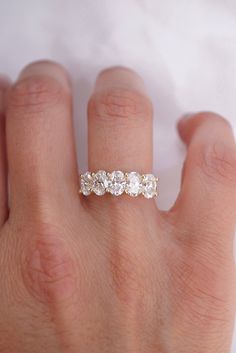 a woman's hand with a three stone diamond ring on top of her finger