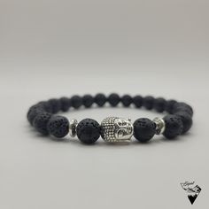 Bring a touch of serenity and sophistication to your outfit.The 8mm Buddha Head Lava Bead Bracelet is the versatile accessory you need. This handcrafted bracelet is custom made to fit your wrist perfectly. The number of beads varies depending on the size requested (approx. 25 beads for an 18cm wrist) The Buddha Head Lava Bead Bracelet is an elegant and spiritual accessory that will bring a touch of serenity and sophistication to your outfit. The black beads, made of lava stone, are recognizable by their porous and rough texture, adding a natural dimension to the bracelet. The small silver or gold metal Buddha head is finely detailed, adding a spiritual dimension to the bracelet. It will be placed between two small pearls matching the color of the Buddha's head (Silver or gold). The overall Hand-strung Lava Stone Bracelets, Casual Bracelets For Meditation With 8mm Beads, Casual Bracelets With 8mm Beads For Meditation, Casual 8mm Beaded Bracelets For Meditation, Adjustable Lava Stone Bracelet For Meditation, Adjustable Lava Stone Stretch Bracelet For Meditation, Meditation Bracelets With Natural Lava Stones, Hand-strung Lava Stone Bracelets With Round Beads, Spiritual Lava Stone Bracelets With 8mm Beads