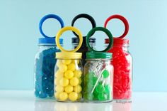 four glass jars with candy in them and olympic rings on the top one is filled with jelly beans