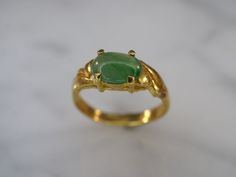 22k yellow gold and green jade ring is a size 4 1/2. An 8mm x 6mm oval jade cabochon is set in a four prong gallery setting with a high polish finish. Band tapers from 5mm at top to 3mm at bottom. No stamp. Green Jade Ring, Oxidized Brass, Gold And Green, Jade Ring, Green Jade, Photo Bracelet, Jade Green, Flower Shape, Cut Glass