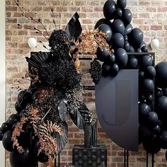 black balloons and decorations in front of a brick wall