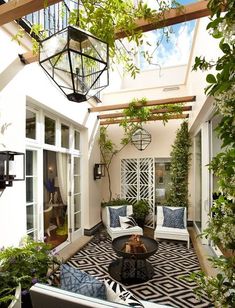 an outdoor living area with couches, tables and potted plants on the floor