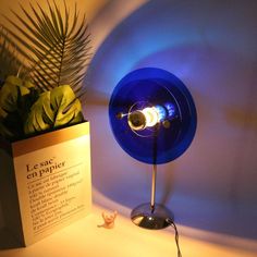 a blue table lamp sitting next to a plant