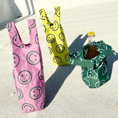 three bags with smiley faces on them are sitting in the parking lot next to a soda bottle