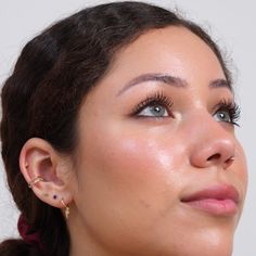 a close up of a woman with ear piercings on her ears and wearing an earring